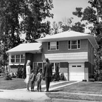 Pogled sa srednjim odraslim osobama koji stoji sa svojom dvoje djece ispred kućnog postera